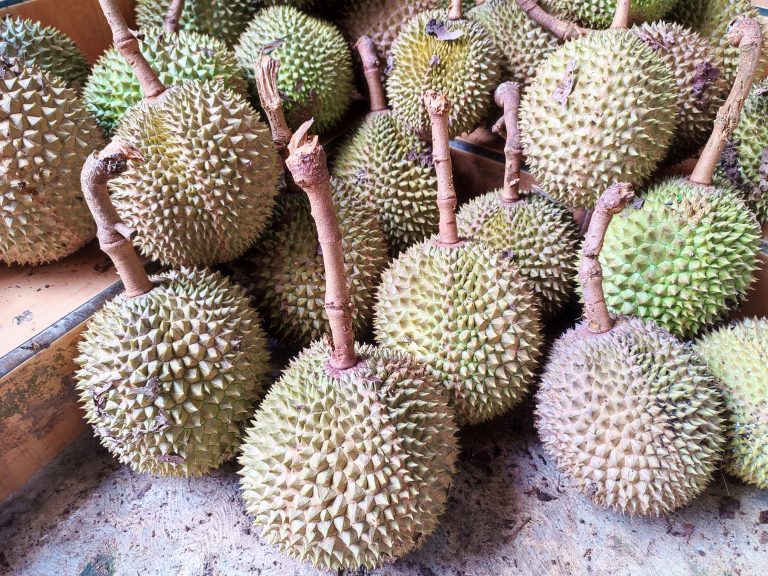 Durian fruit stacked on a table.