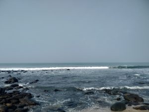 A serene ocean view from a rocky shore, showcasing the beauty of the blue sky, blue ocean, and white waves.