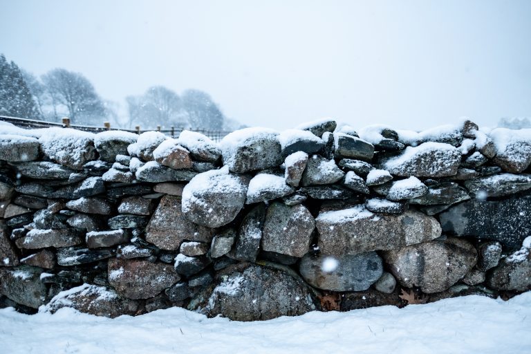 Some white powdery snow rests on an old stone wall in Little Compton, Rhode Island during the winter of 2021.