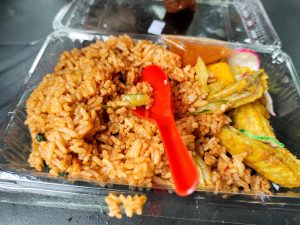 A plastic container filled with a delicious mix of rice and colorful vegetables.