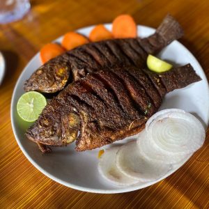 View larger photo: Karimeen fish fry Kerala-style, fried fish with onions, carrots and limes