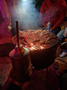 People gathered around a barbecue where meat is cooking