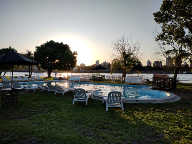 A pool besides a river and white chairs around it. Pileta Club Marina Puerto Santa Fe Argentina.