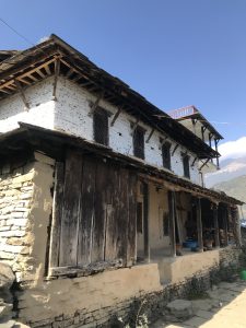 Traditional old white brick house with a large porch, blue sky, and mountains in the background