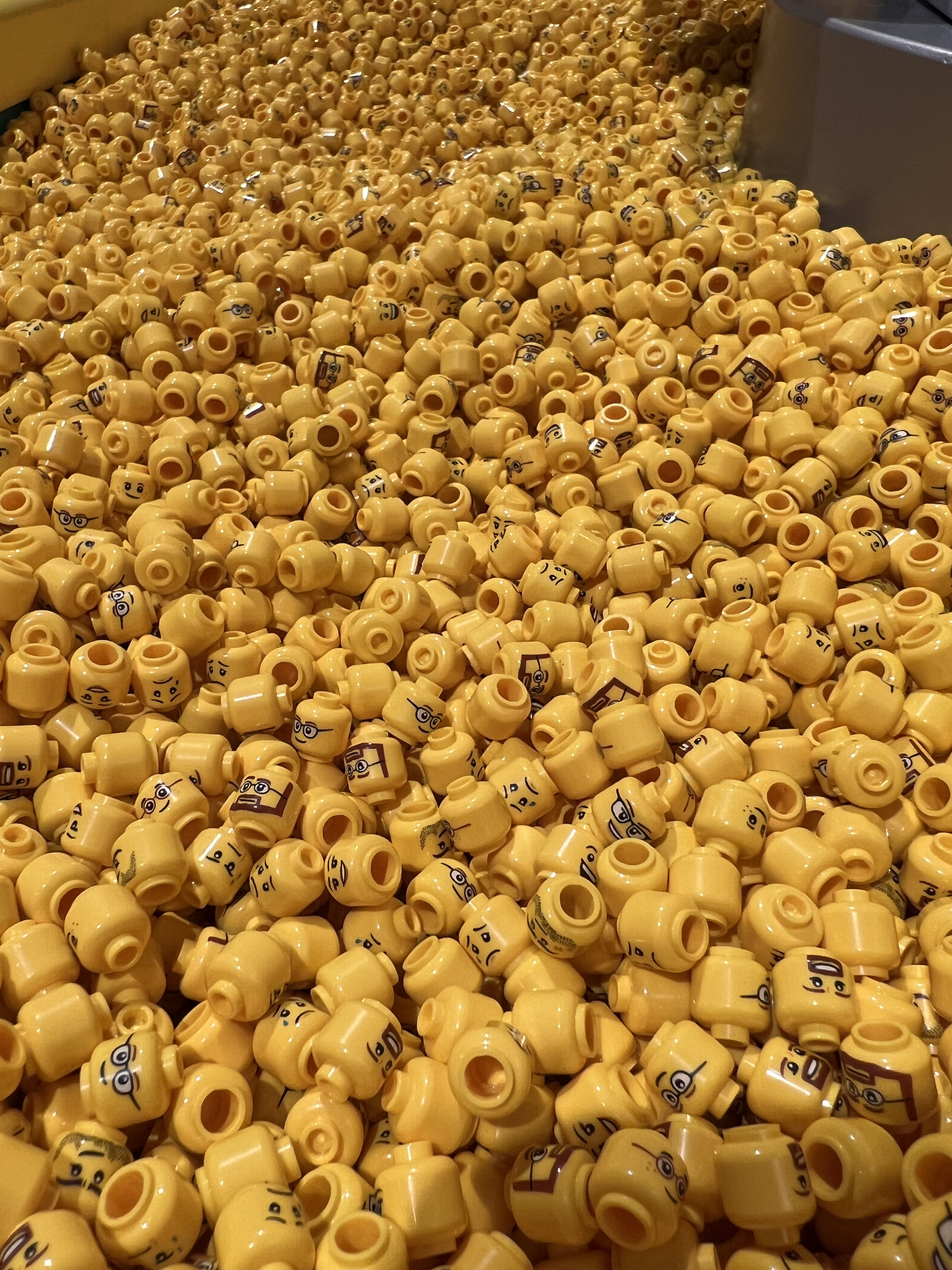 Thousands of different Lego character heads in a bin.