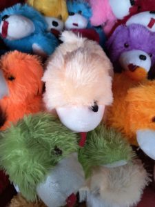 Adorable teddy surrounded by a variety of teddies in a charming, vibrant teddy shop.