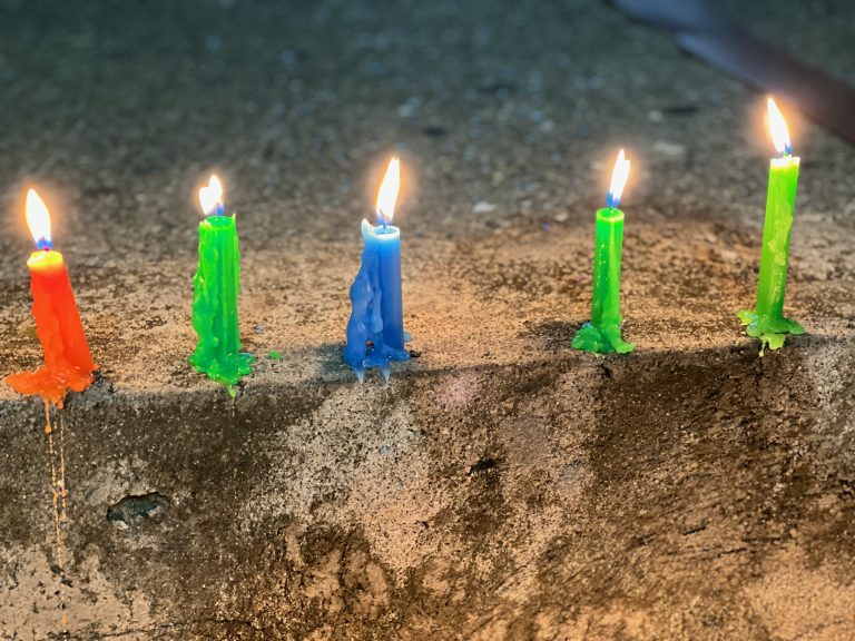 Colorful candles burning and dripping down from Noche de las Velitas (Night of the Little Candles) – a Colombian holiday in December.