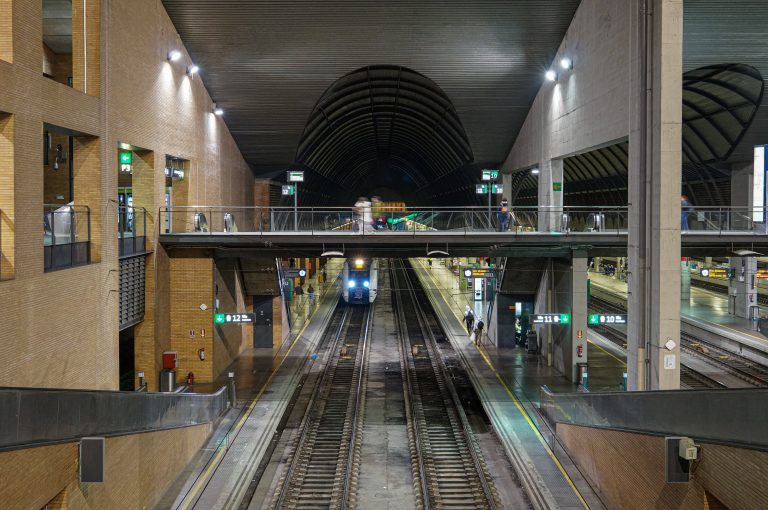 Train station interior, with train, stopped at the end of the tracks.