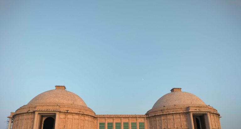 Two domed roofs of a building with a vast blue sky