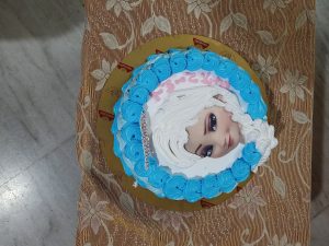 A birthday cake with an image of a Disney princes Elsa. 