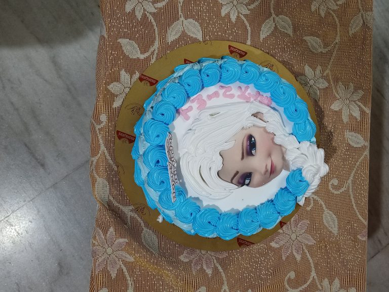 A birthday cake with an image of a Disney princes Elsa.