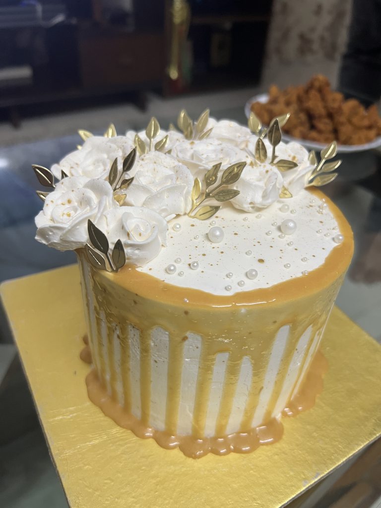 Homemade cake with white frosting and gold decorations, perfect for a special occasion or celebration.