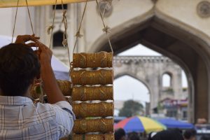 A man hanging bangles and bracelets in a marketplace