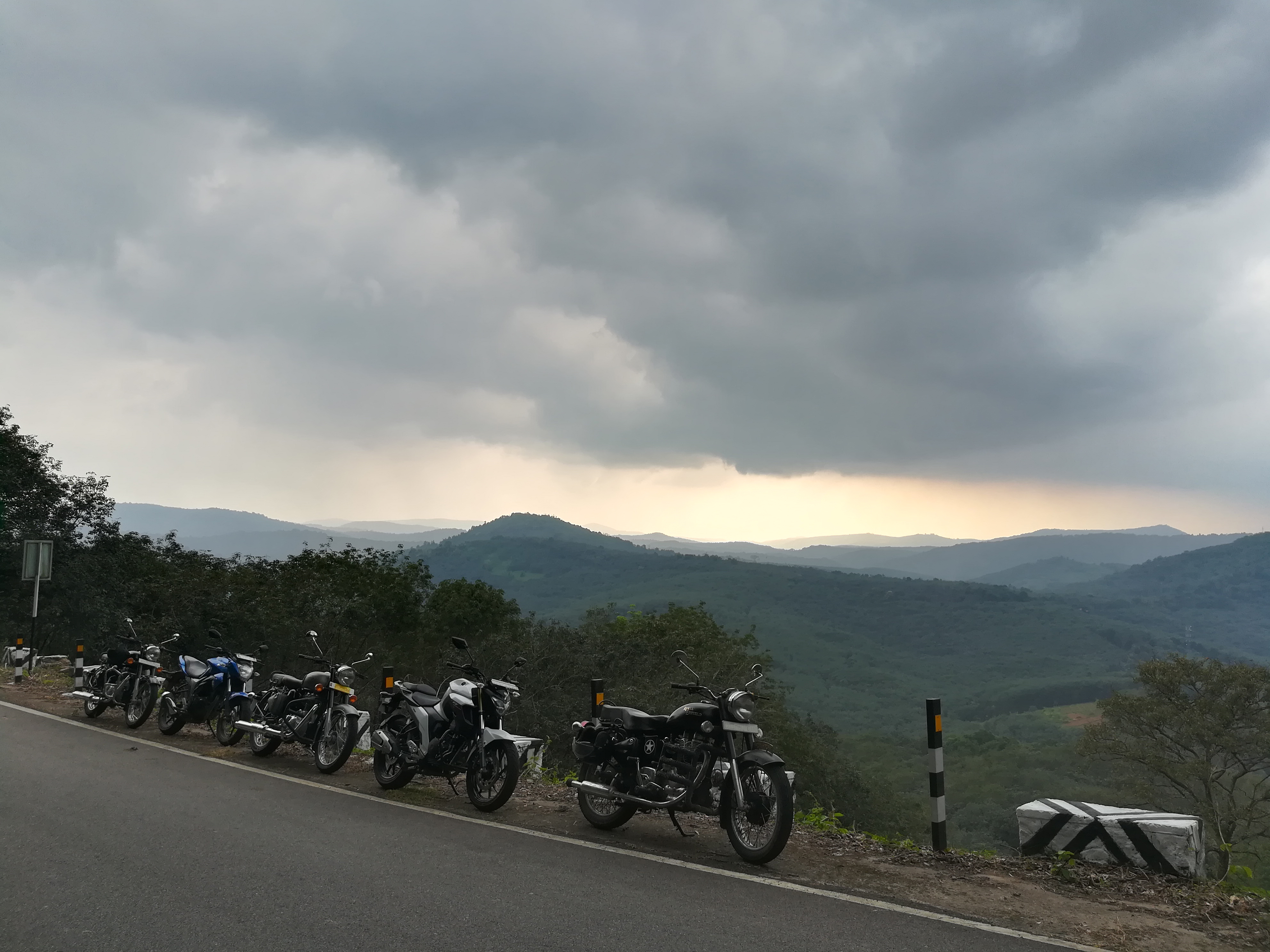 Motorcycles parked on the side of a road with mountains in the background