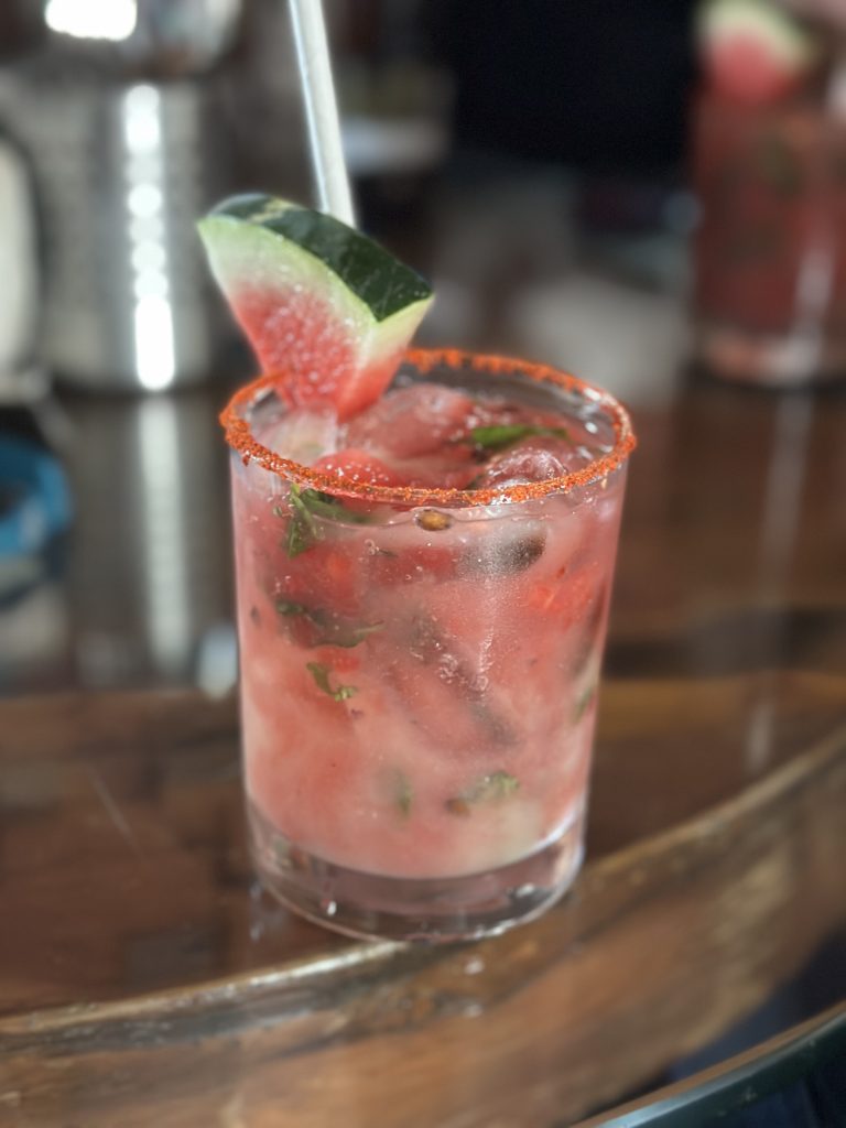 A watermelon cocktail, a fusion of sweet fruit and a hint of mint, rimmed with spices