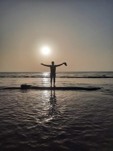 This photo captures a tranquil moment when a lone man stands in the calm waters of the ocean.