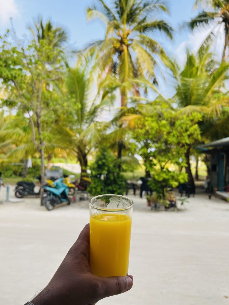 A glass of pure orange juice with palms trees and motorcycles in the background