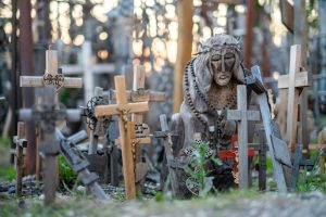 Wooden Jesus sculpture surrounded by small crosses in the Hill of Crosses, Lithuania.