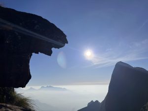 Tiger rock at Kolukkumalai, a famous spot in Idukki, Kerala. The rock (that looks like a pouncing tiger) is silhouetted against a bright blue sky