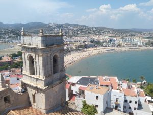 A belltower rises above the beach and water in Pe?íscola, Spain