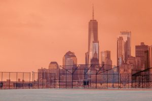 An infrared photo of a baseball field with the skyline of lower Manhattan in the background. 
