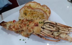 The lobster served on a white ceramic plate, along with toasted bread.