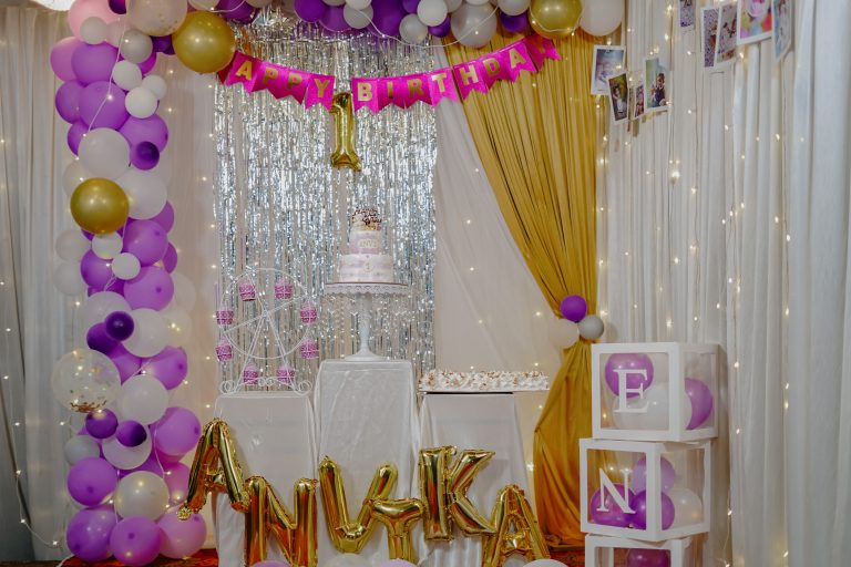 Birthday stage decorated with balloons, photos, and cake in the centre,