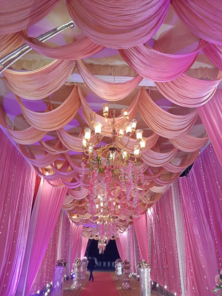 Chandelier hanging among pink draperies on the ceiling and walls