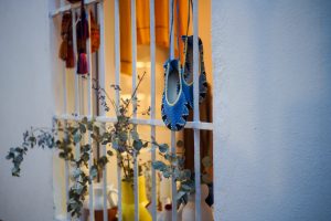 Blue hand-knitted slippers hanging from a window.