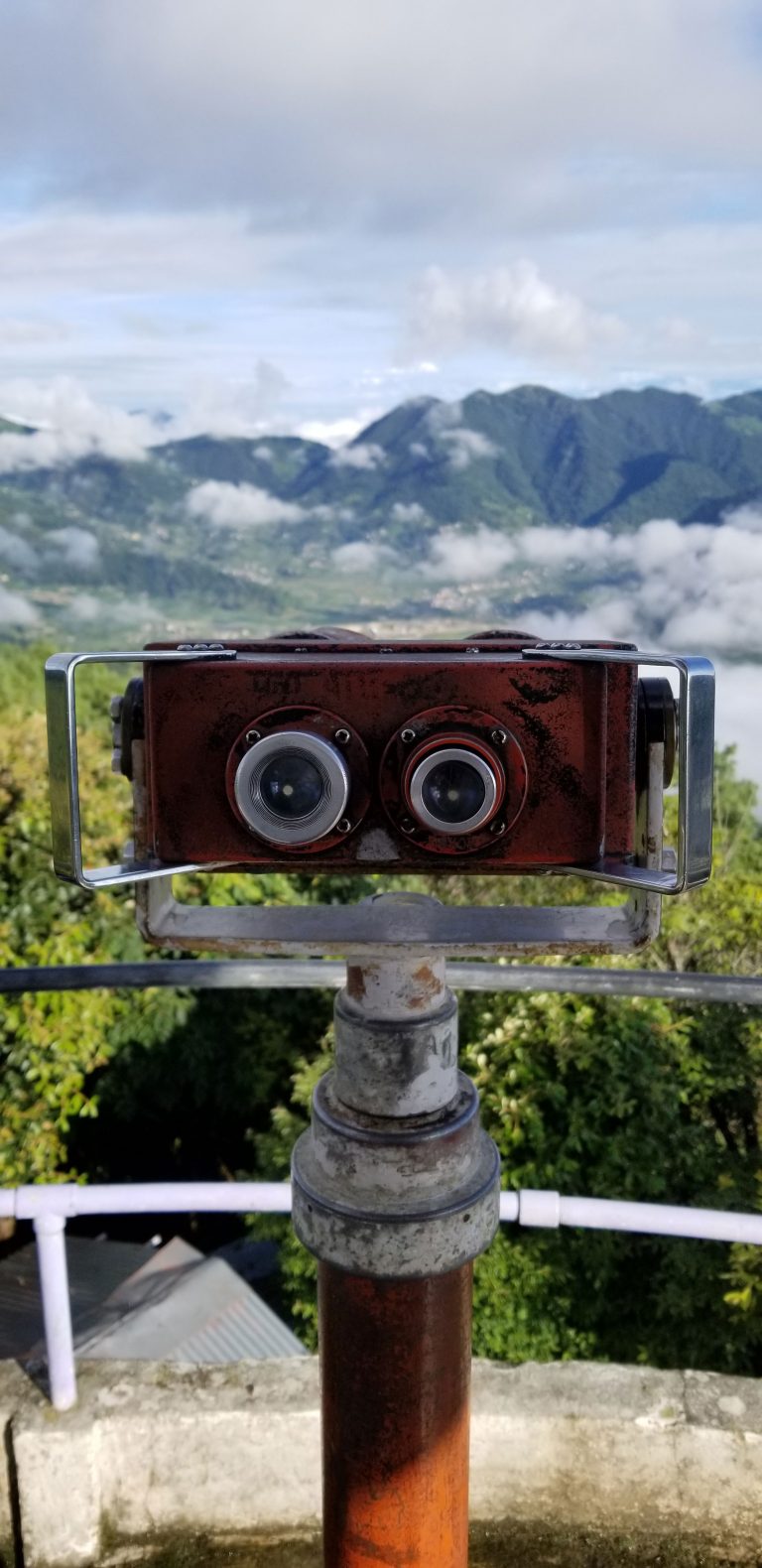 Using binoculars from the height of the tower to admire the beautiful mountains.