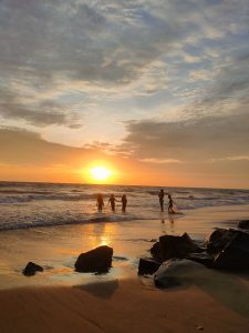 Children at Kozhikode Beach joyfully play in the warm golden glow of the sunset, casting long shadows on the waves, creating a serene scene of joy and freedom.