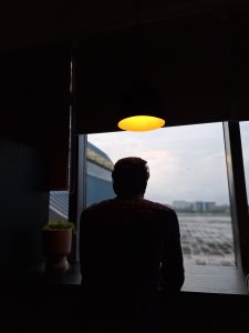 A man sitting under a light looking into the horizon.
