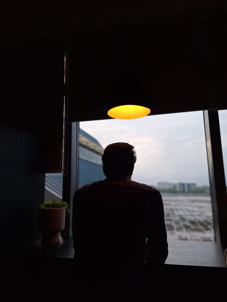 A man sitting under a light looking into the horizon.