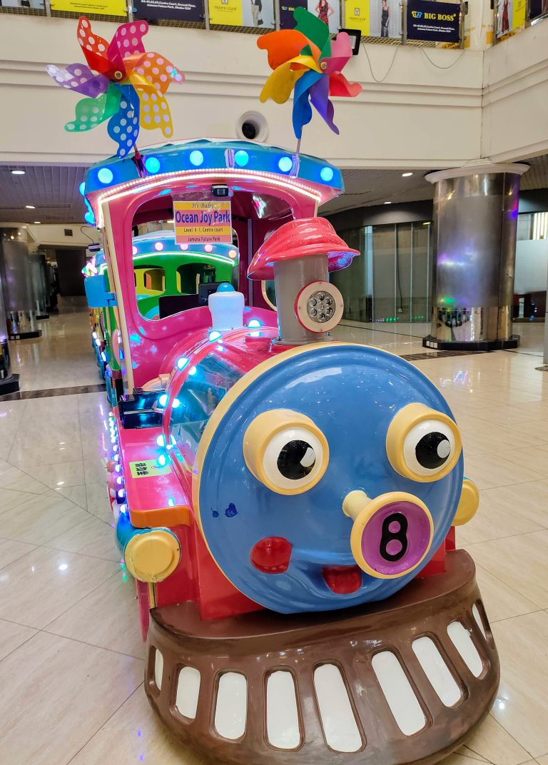 A toy train with a smiling face on the front, chugging along the tracks.