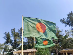 A green and red Bangladeshi flag on a pole.
