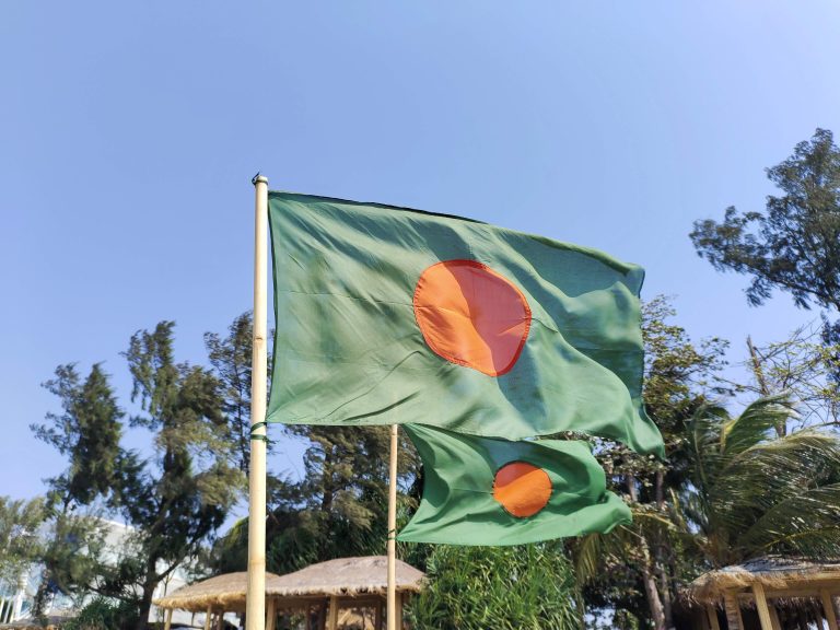 A green and red Bangladeshi flag on a pole.