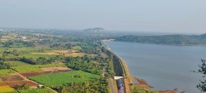 Aerial view of a dam and levee with water to the right and farmlands to the left