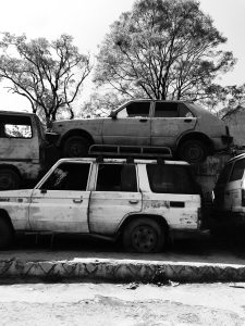 A white jeep with a car stacked on top of it.