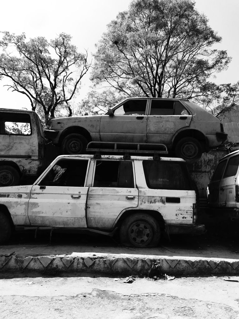 A white jeep with a car stacked on top of it.