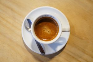 Top view of a cup of coffee on a light wooden table