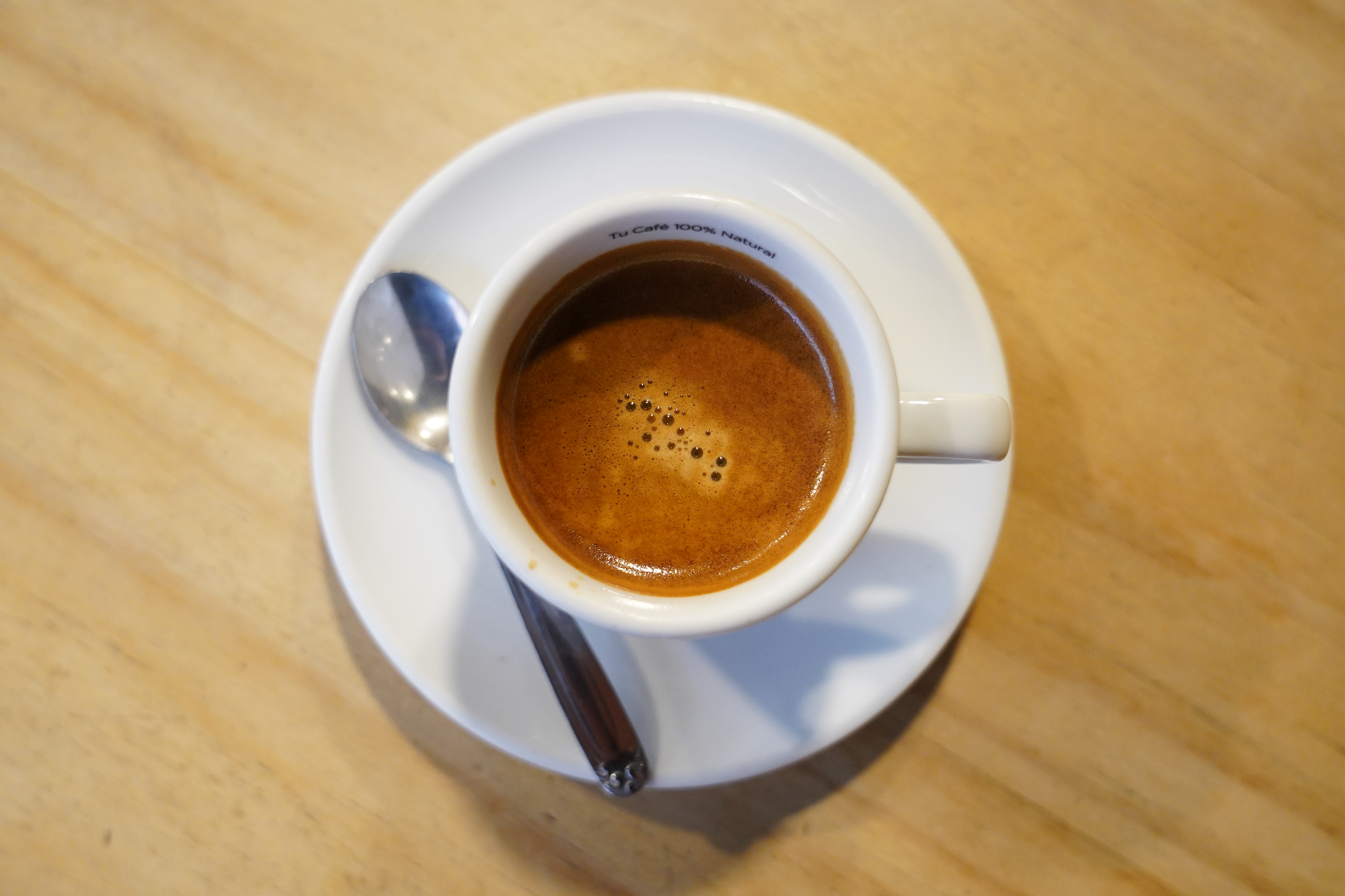 Top view of a cup of coffee on a light wooden table
