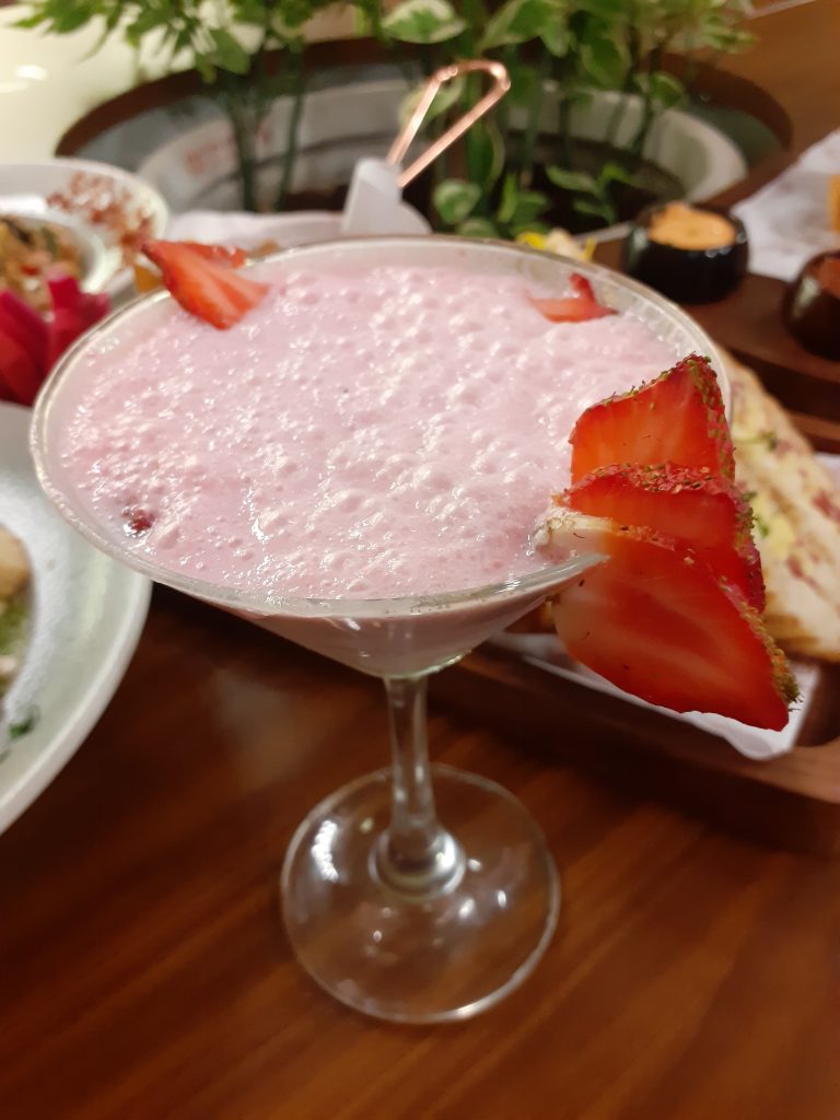 A pink mocktail with strawberries on the rim