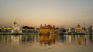 Night view of illuminated golden temple and its relfection in the water.