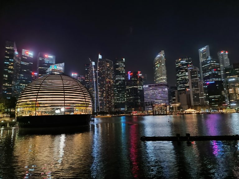 City skyline at night with water in the foreground. Apple Center Singapore with stunning buildings.