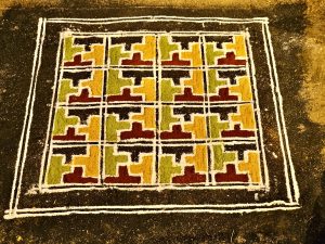 A decorative, patterned piece of art made on the ground, drawn free hand using the medium of rice flour coloured with herbs. Designed during temple rituals. It is known as The Kalam. Kozhikode, Kerala.