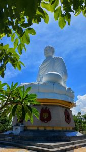 A large white budha statue having a blue sky background. Photo taken from Nha Trang, Vietnam.
