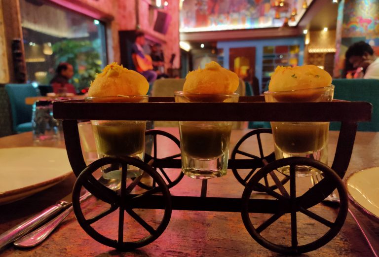 Spirited Fusion: A tantalizing photo capturing vodka pani puri served over a cart, with individual glasses of vodka pani and puris, showcasing a creative and delectable blend of flavors.