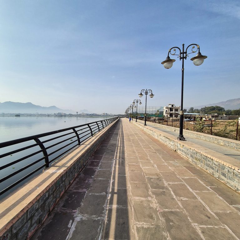 A riverside pathway with light lamps and railings.