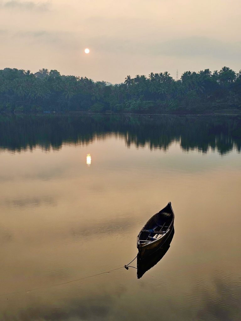 A sunrise view from the banks of Chaliyar river and a boat in the calm river. Located in Perumanna, Kozhikode, Kerala.