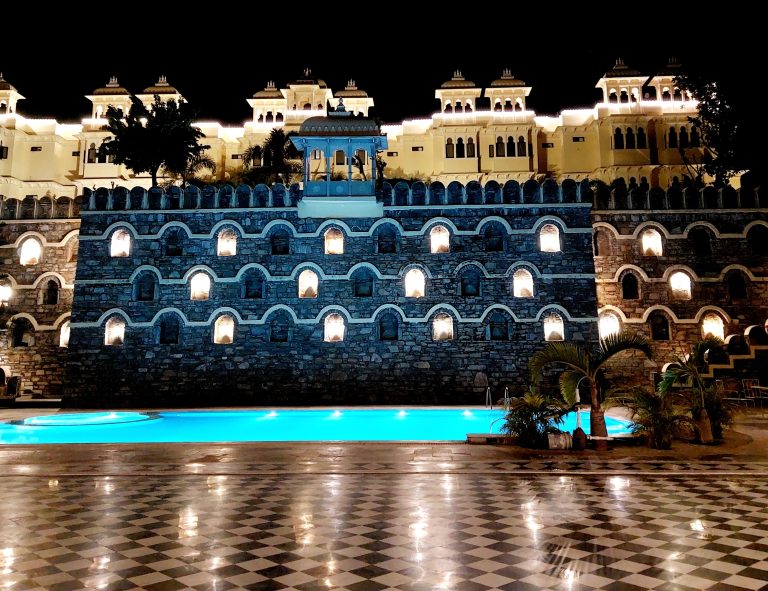 Buildings lit up at night, with a swimming pool in the foreground